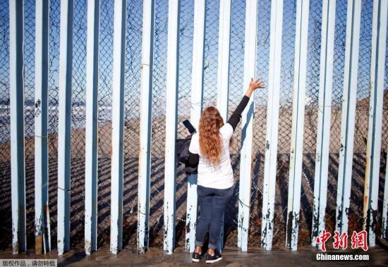 资料图：当地时间2018年12月8日，墨西哥提华纳，墨西哥女子Claudia Alvarez站在美墨边境墙墨西哥一侧向美国圣地亚哥一侧的老公和儿子打招呼。Alvarez说，五年来，她一直试图获得赴美签证，以便与丈夫和儿子生活在一起，但她的签证申请被拒绝了。